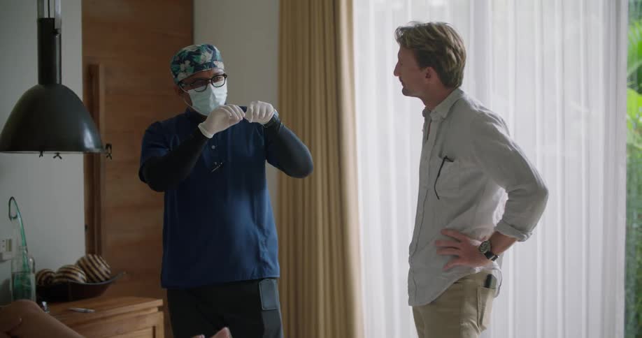A medical professional gestures with his hands to explain a technique to another man