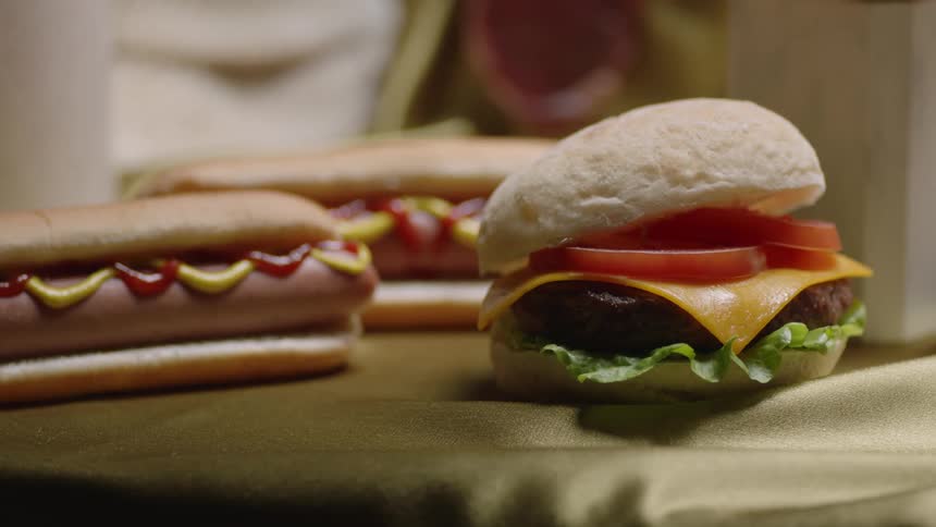 A cheeseburger and hotdogs in buns sitting on a table
