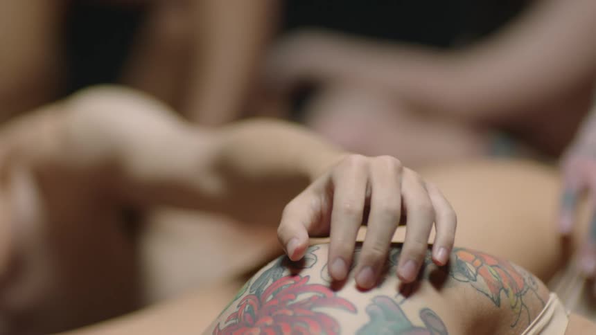 A woman runs her fingers over her partners tattooed shoulder