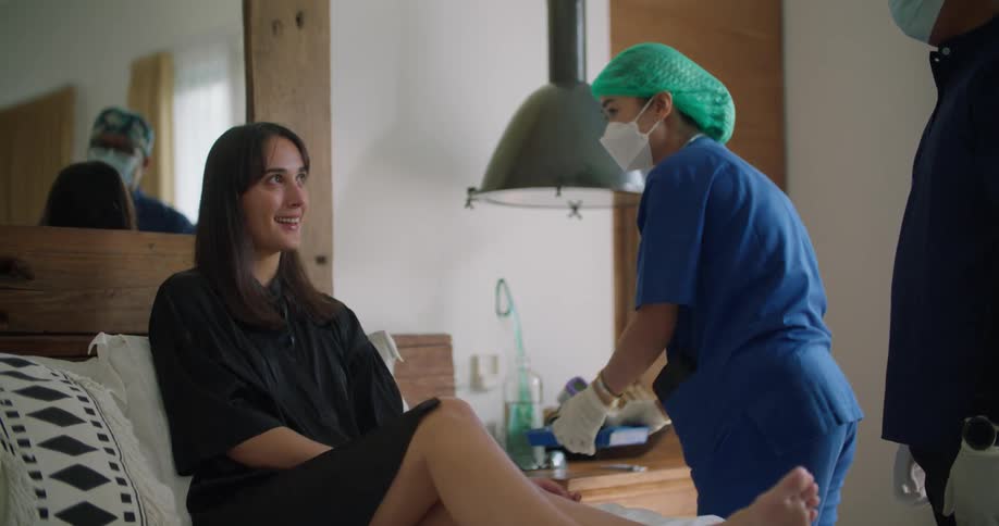 A female patient sits in bed as two medical professionals attend to her