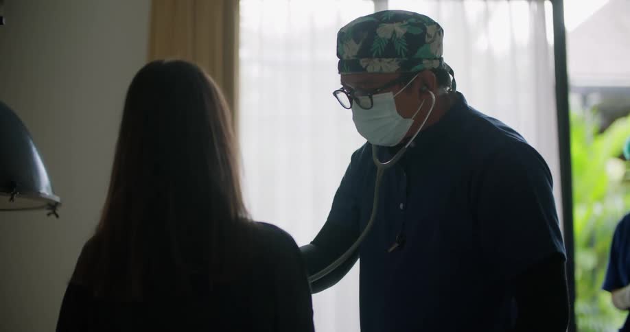 A doctor checks a patients heartbeat during a house visit