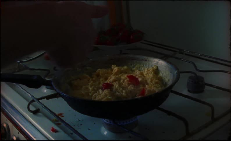 A man throws tomatoes into a dish being cooked on the stovetop