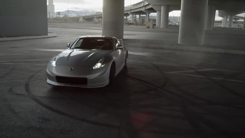 A sports car sits parked beneath a freeway