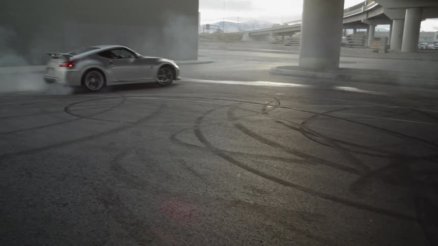 A car does donuts under a bridge