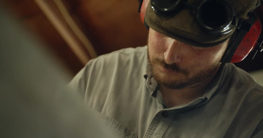 A man wearing hearing protection ear muffs looks down while working