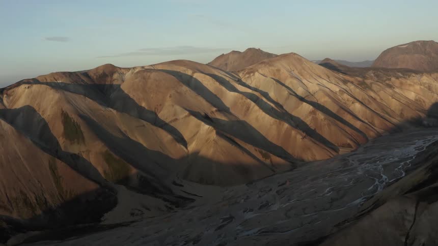 Sunlight and shadow create stripes on sandy ridges above a valley