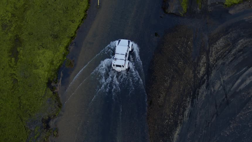 A vehicle drives down a flooded road