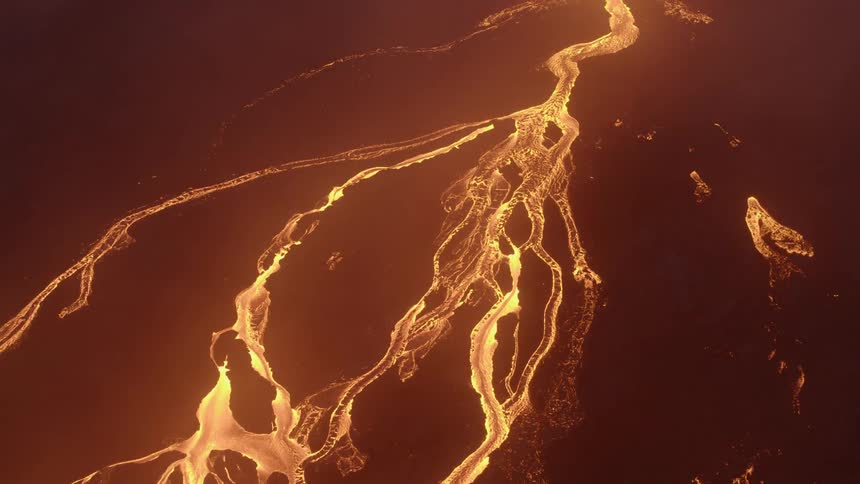 Streams of lava flow down the slopes of a volcano at night