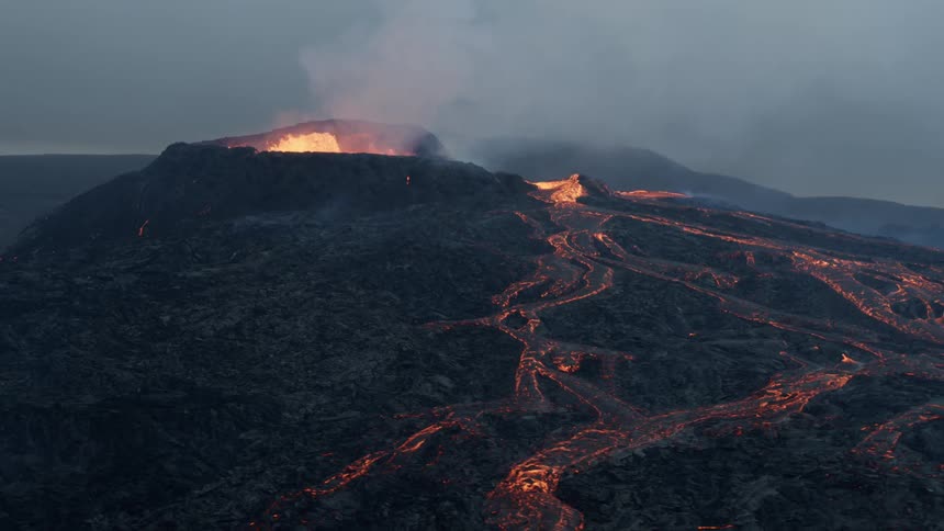 Lava is bubbling at the top of a volcano and flowing down the sides