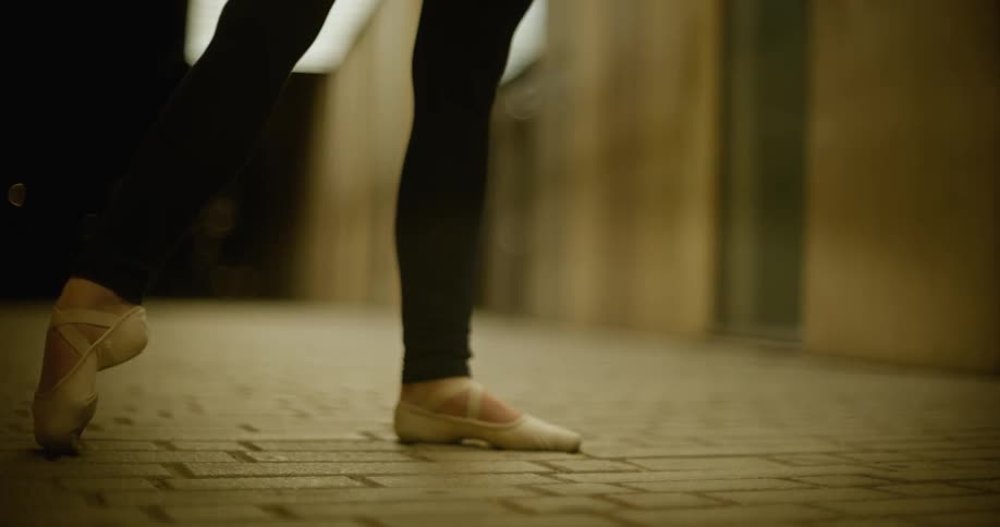 A ballet dancer practices outside a building at night