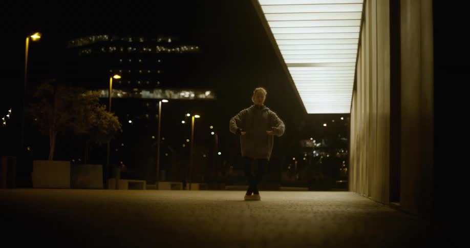A ballerina dances outside in a city at night