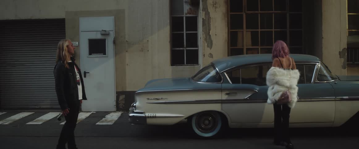 Two people standing out next to a car
