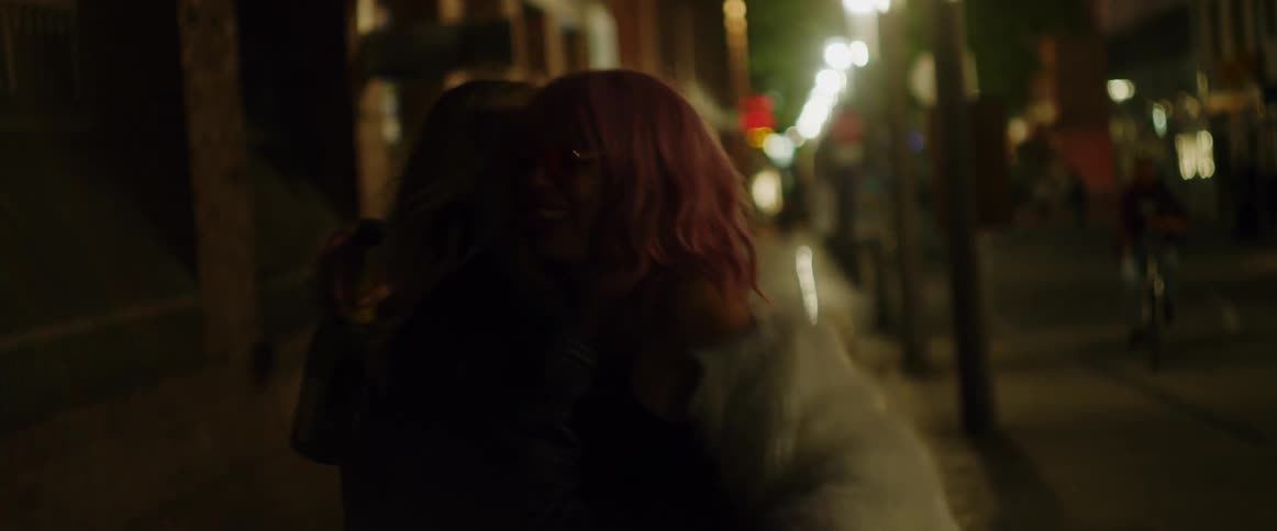 A woman drunkenly hugs a friend after running into each other on a city street