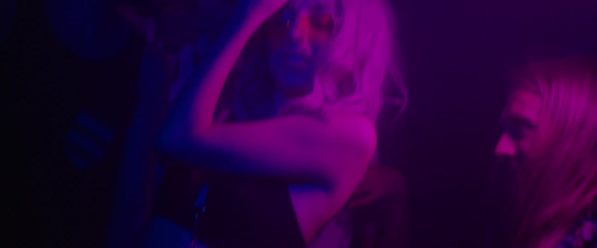 A group of friends laugh while dancing in a nightclub