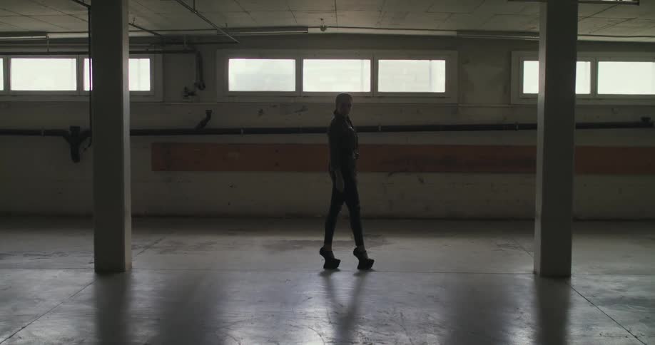 A woman is standing in an empty room wearing platform shoes