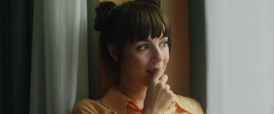 A woman smiles as she sits in a window sill with a book