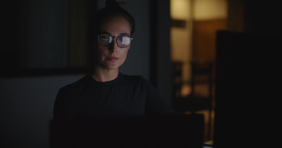 A young white woman is on her computer inside of her room