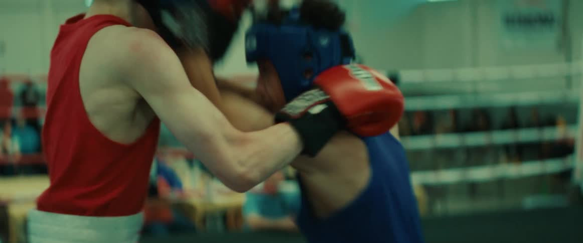 Two men boxing throw punches as a referee and spectators watch