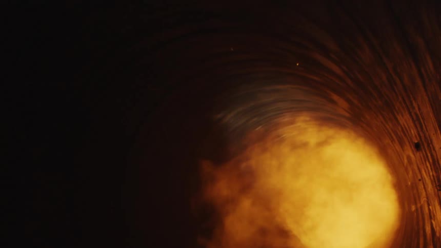 Flames illuminate the sides of a dark tunnel as they emerge in a fiery blast