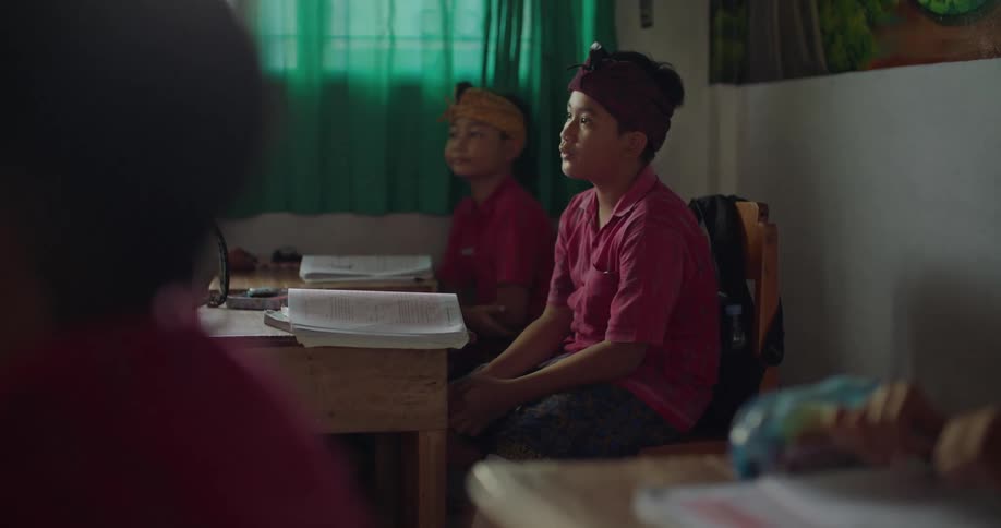 Students listen and nod while sitting at desks in classroom