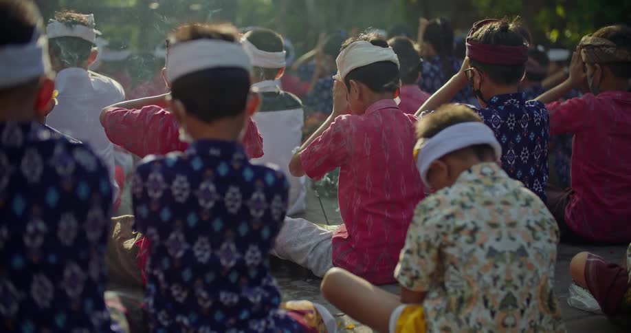 Young boys pray with the heads down while sitting outside