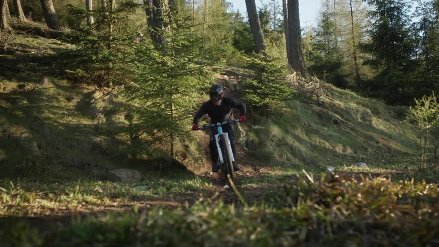 A young white man is riding a bike during a path in the woods