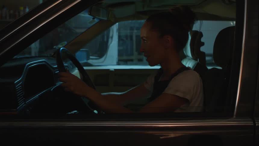 Woman sitting on the drivers seat of a parked car sighs in relief when it turns on