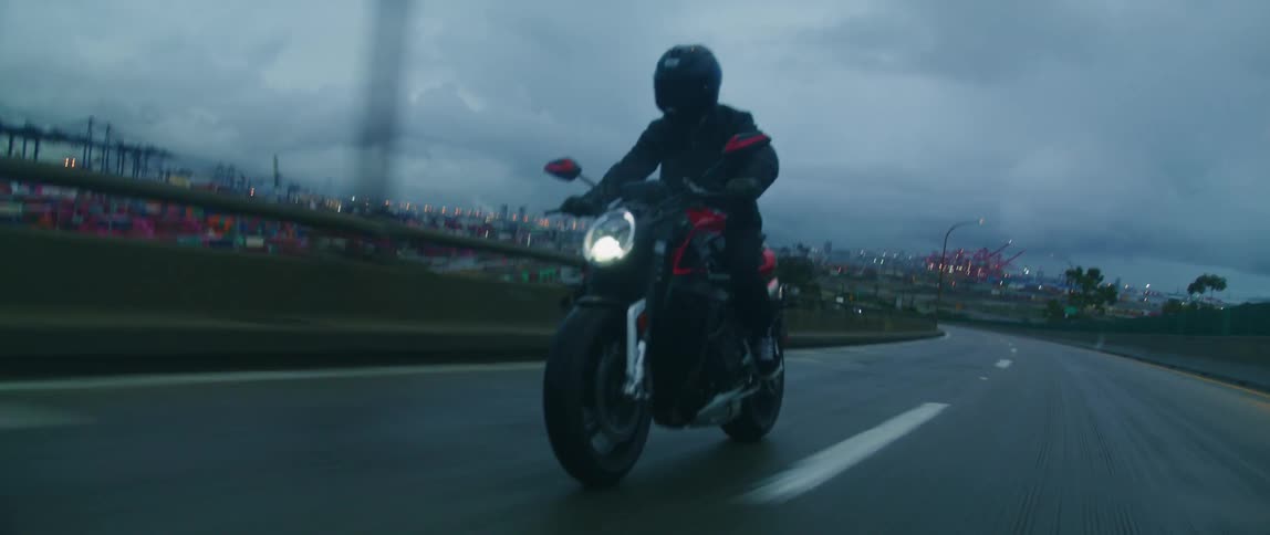 A motorcyclist speeds past a marina