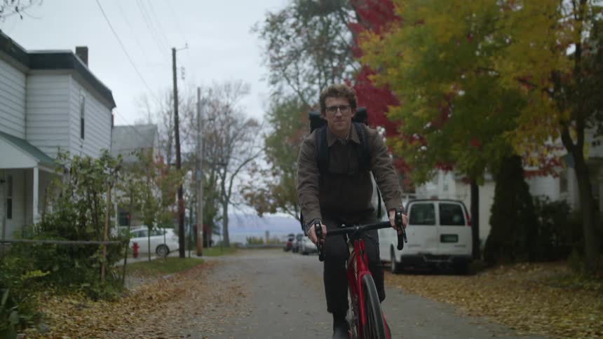Man driving a red bicycle on the road of a neighborhood