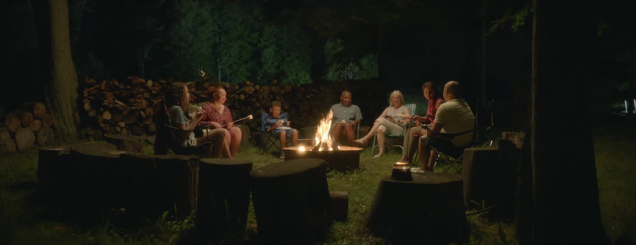 Friends are camping outside and cooking smores at night