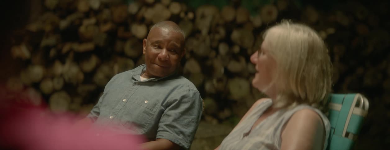 A relaxed mature couple relaxing outdoors on a campfire talk to each other