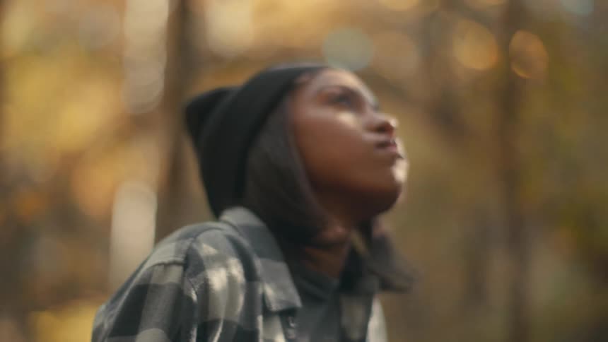 A woman is looking up in the forest