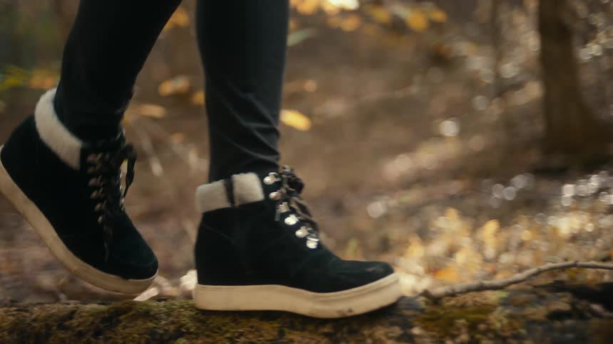 A person walking outdoors on a log