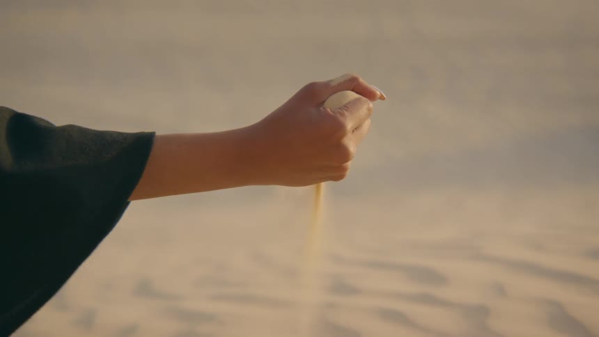 A person drops some sand in the desert