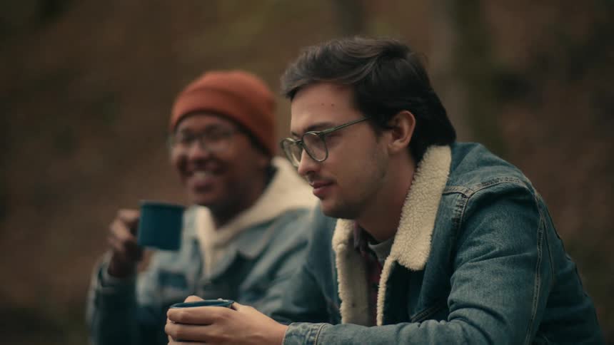 Two men laugh and drink outside
