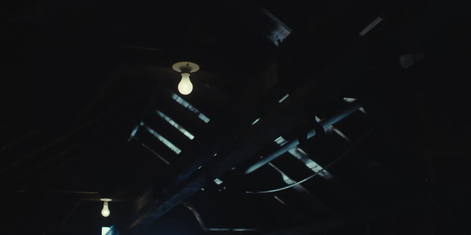 An incandescent light bulb on the ceiling of a dark corridor