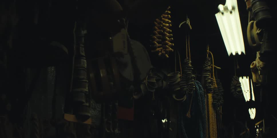 Florescent light fixture on a ceiling with tools and ropes hanging down