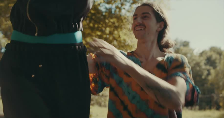 A man holds a woman at the waist to help her balance on a tight rope then lifts her off