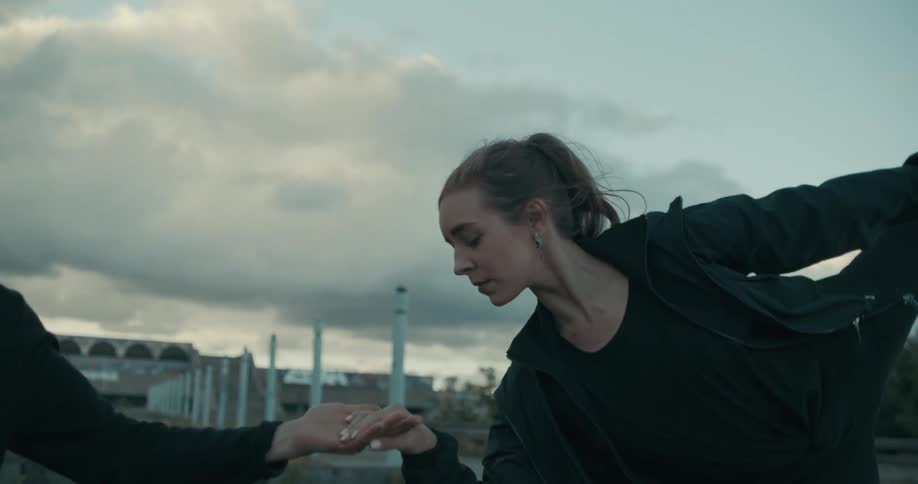A woman dancing takes a mans hand and lifts her leg high in the air