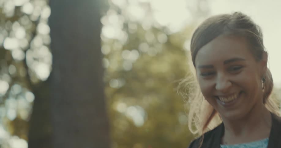 A man and woman laugh while slow dancing in the woods