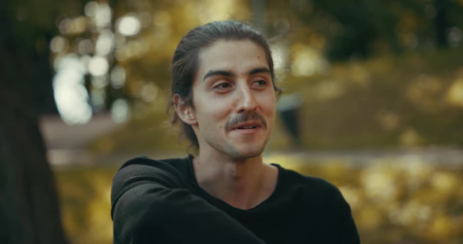 A man sits under a tree an smiles and talks