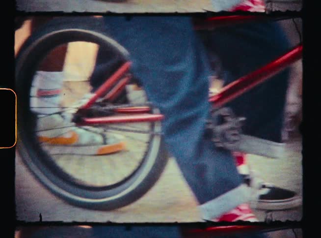 Vintage footage of the legs of kids sitting on bikes