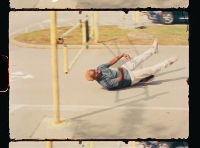 A young man rides a skateboard sitting going under the parking lot gate laughing