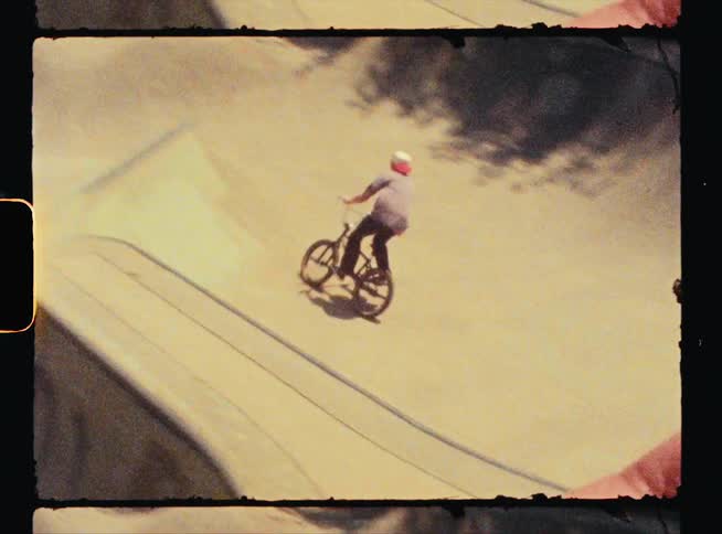 A man rides a bicycle down a ramp in a skate park