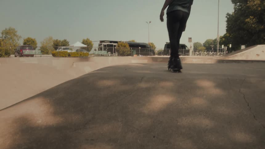 A young man skateboards across a narrow ledge and down a ramp at a skateboard park