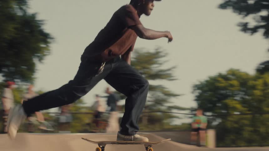 A young man pushes off and rides his skateboard on a ramp in the skatepark