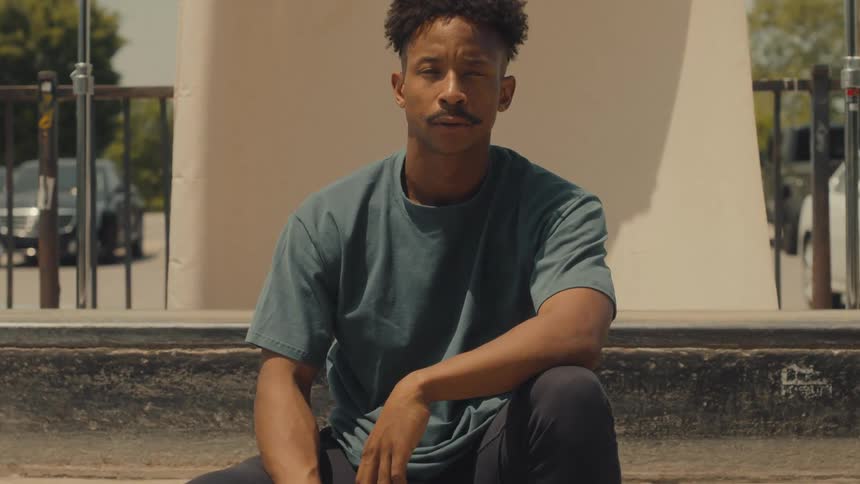 A young man sits outside and poses for a portrait