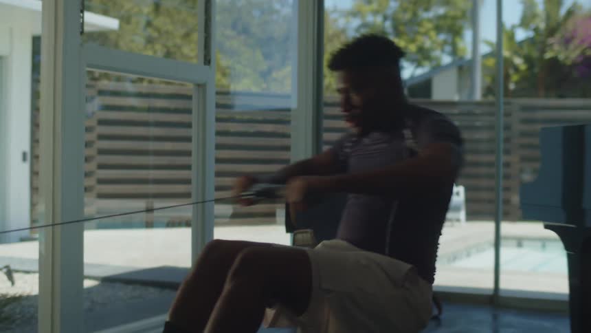 A man is exercising on a workout machine indoors