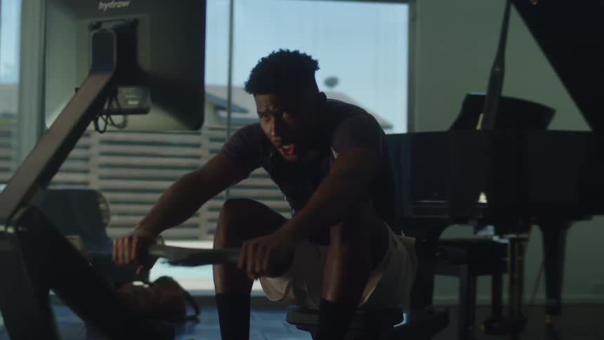 A man at home rows on a rowing machine