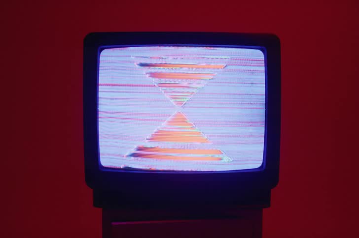 Blue and white tones of changing patterns on television screen contrast with the red background